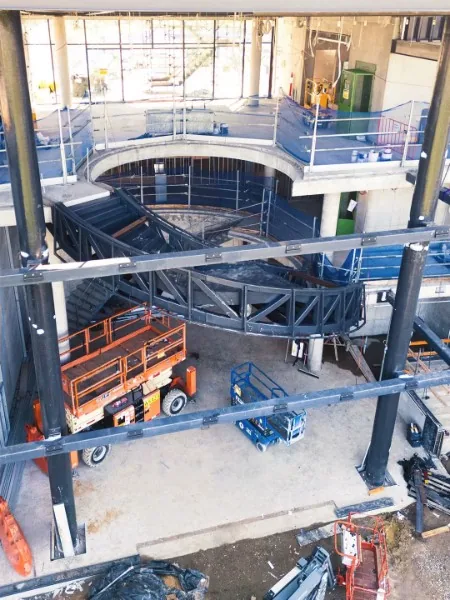 Structural steel framing and curved staircase installed inside a multi-level construction project